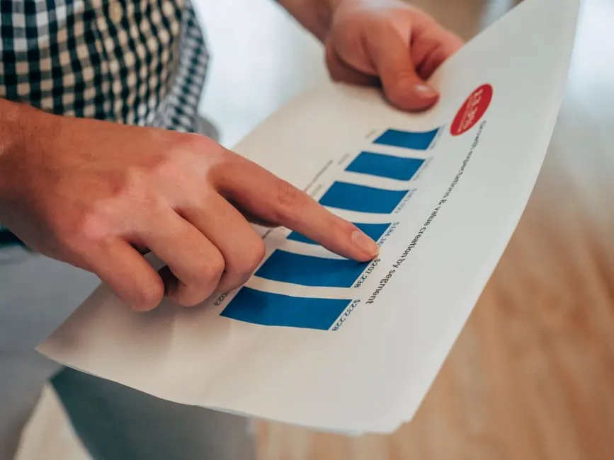 Tableau de trésorerie mensuel avec colonnes entrées sorties et solde, posé sur un bureau clair